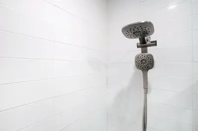 a shower head in a white tiled bathroom at 444-4F Newly renovated 1BR in Midtown West in New York