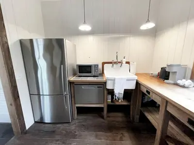 a kitchen with a stainless steel refrigerator and a sink at Cottage Retreat - Historic Cottage Home w Home Gym in Cornwall