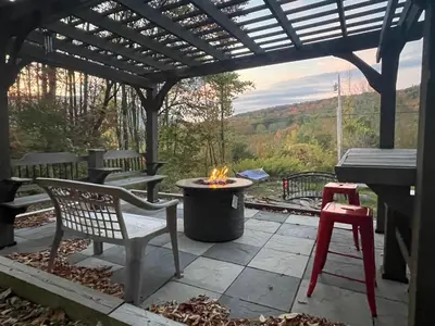 a patio with a fire pit under a pergola at Catskill Mountain Retreat in West Kill