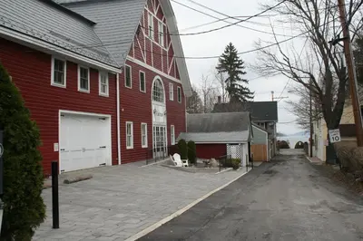 a red barn with a driveway in front of a house at Visions Inn in Cooperstown
