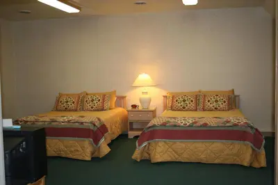 a hotel room with two beds and a lamp at Visions Inn in Cooperstown