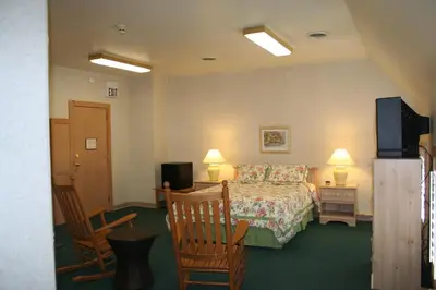 a hotel room with a bed and two chairs at Visions Inn in Cooperstown