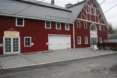 a large red barn with a white garage at Visions Inn in Cooperstown