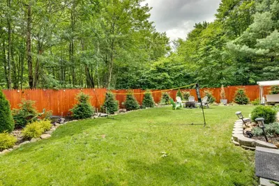 a backyard with an orange fence and a grass yard at Hot Tub, Game Room and Fire Pit Pocono Summit Home! in Pocono Summit