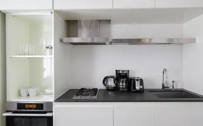 a white kitchen with a stove and a sink at Stylish 1BD near Bryant Park with Washer and Dryer in New York