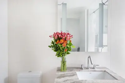 a vase of flowers sitting on a counter in a bathroom at Stylish 2BD with Washer and Dryer near Times Square in New York