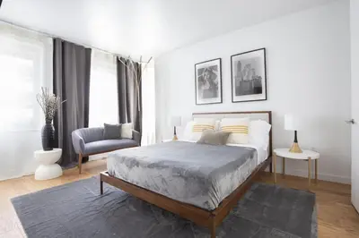 a white bedroom with a bed and a chair at Beautiful 2BD Apartment near Times Square in New York