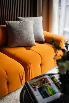 an orange couch with pillows in a living room at Stunning 2BD Penthouse in Chelsea w Washer and Dryer in New York