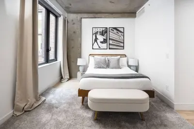 a bedroom with a large bed and a ottoman at Stunning 2BD Penthouse in Chelsea w Washer and Dryer in New York