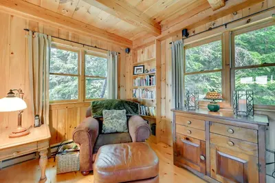 a living room with a chair and a desk and windows at Lakefront Westhampton Cabin with Beach and Kayaks! in Westhampton