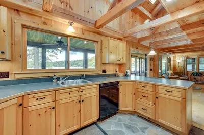 a large kitchen with wooden cabinets and a sink at Lakefront Westhampton Cabin with Beach and Kayaks! in Westhampton