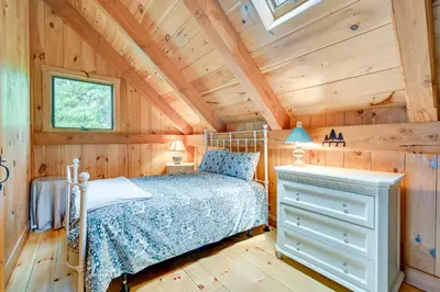 a bedroom with a bed and a wooden ceiling at Lakefront Westhampton Cabin with Beach and Kayaks! in Westhampton