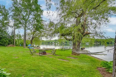 a picnic table and chairs under a tree next to a lake at Lakefront Westhampton Cabin with Beach and Kayaks! in Westhampton