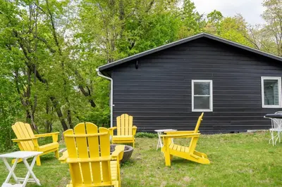 a group of chairs in front of a black house at Campfire Cottage Fireplace, fire pit & no chores! in Kingston