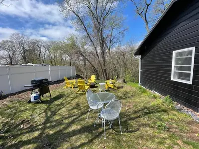 a backyard with tables and chairs and a grill at Campfire Cottage Fireplace, fire pit & no chores! in Kingston
