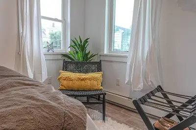 a bedroom with a bed and a chair and windows at Campfire Cottage Fireplace, fire pit & no chores! in Kingston