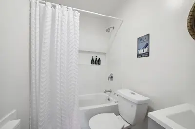 a white bathroom with a toilet and a bath tub at Marine Theme - 4 BR - Backyard - Fire pit in Bridgeport