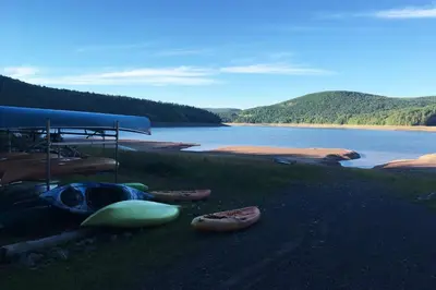 a group of boats sitting on the grass next to a lake at Mountain-Top-Hideaway Stay in a log cabin on a private rd! Swim, hike, explore a true mountain experience in North Blenheim