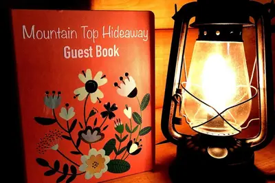 a lantern sitting next to a guest book at Mountain-Top-Hideaway Stay in a log cabin on a private rd! Swim, hike, explore a true mountain experience in North Blenheim