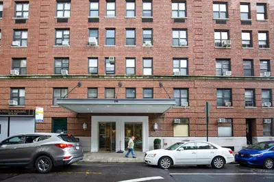 a woman walking in front of a brick building at Upper W Side 1BR w Gym by Lincoln Sq NYC-331 in New York