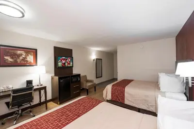 a hotel room with two beds and a desk at Red Roof Inn PLUS+ Poughkeepsie in Poughkeepsie
