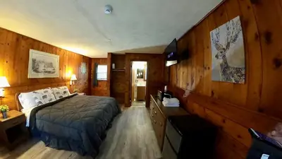 a bedroom with a bed and a wooden wall at Heart of the Berkshires Motel in Pittsfield
