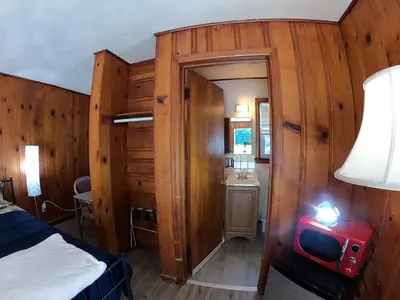 a bedroom with wooden walls and a bed and a mirror at Heart of the Berkshires Motel in Pittsfield