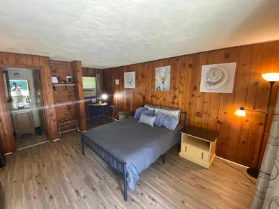 a bedroom with a bed in a room with wooden walls at Heart of the Berkshires Motel in Pittsfield