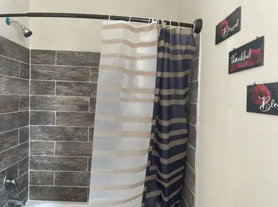 a shower with a striped shower curtain in a bathroom at fashionably cozy place in Meriden