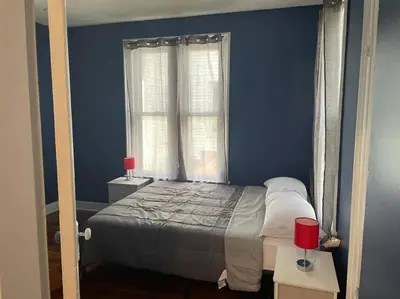a blue bedroom with a bed and a window at fashionably cozy place in Meriden