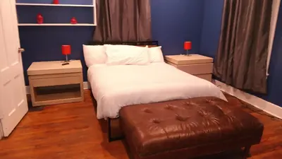 a bedroom with a bed and a brown leather ottoman at fashionably cozy place in Meriden