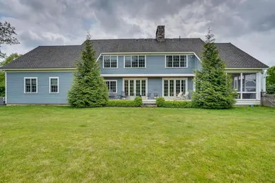 a blue house with trees in front of a yard at Stockbridge Retreat with Pool and Hot Tub! in Stockbridge