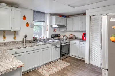 a kitchen with white cabinets and wooden floors at Cozy Berkshires Vacation Rental Near Hiking! in Chester