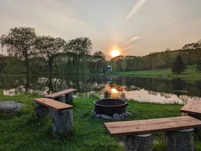 a fire pit and benches next to a lake at Catskills Farmhouse and Spa in Harpersfield