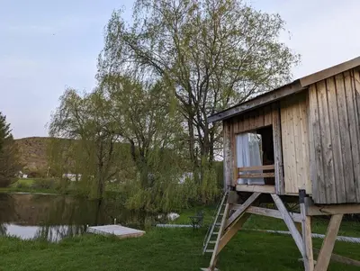 a small shack with a ladder next to a lake at Catskills Farmhouse and Spa in Harpersfield
