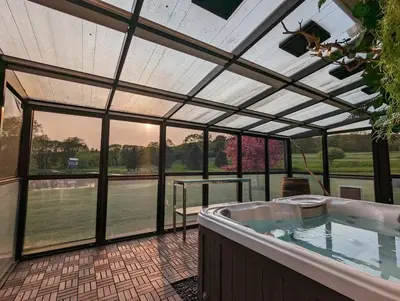a hot tub in a conservatory with a view of a tennis court at Catskills Farmhouse and Spa in Harpersfield