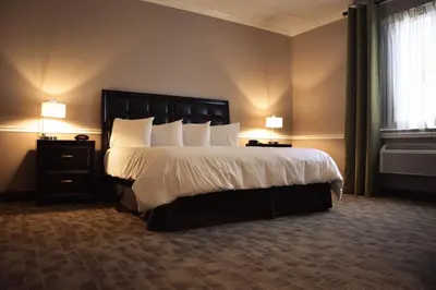 a bedroom with a large bed with white sheets and pillows at Belvedere Inn Schenectady - Albany in Schenectady