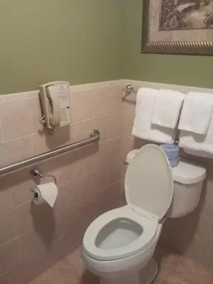 a bathroom with a toilet with towels and a phone at Belvedere Inn Schenectady - Albany in Schenectady