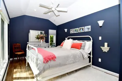 a blue bedroom with a bed and a ceiling fan at Luxury Cottage at Millpond Falls in Warwick