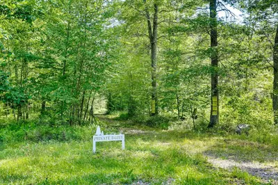a white bench sitting in the middle of a forest at Secluded Poconos Cabin 75 Acres and Fire Pit! in East Stroudsburg