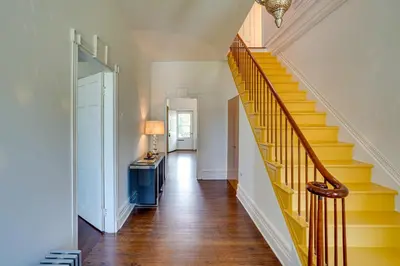 a hallway with a yellow staircase in a home at Historic Home in Coxsackie with Hudson River Views! in Coxsackie