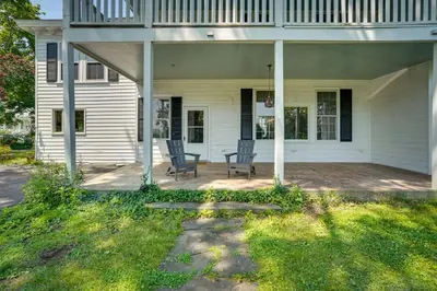 a porch of a white house with two chairs at Historic Home in Coxsackie with Hudson River Views! in Coxsackie