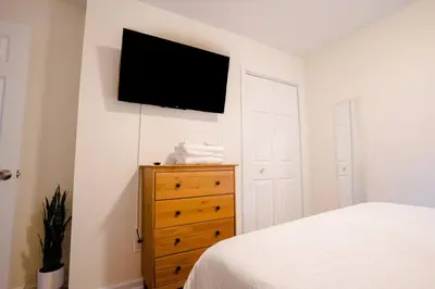 a bedroom with a bed and a dresser with a television on the wall at Saratoga Serenity: Charming Rental Nearby Downtown in Saratoga Springs