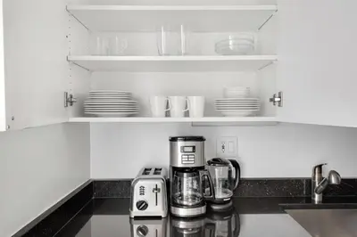 a kitchen counter with a coffee maker and cups and plates at UES 1br w elevator doorman nr Central Park NYC-1186 in New York