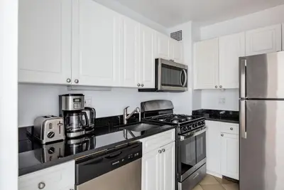 a kitchen with white cabinets and stainless steel appliances at UES 1br w elevator doorman nr Central Park NYC-1186 in New York