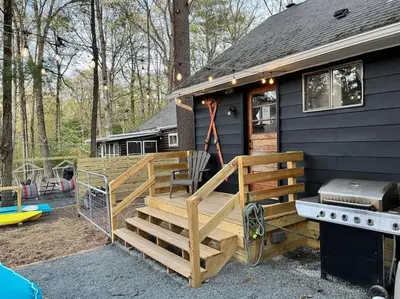 a black tiny house with a deck and a grill at Wally's Compound in Hawley