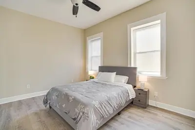 a white bedroom with a bed and two windows at Walk to Dtwn and Waterfront Roomy Troy Apt in Troy