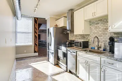 a kitchen with white cabinets and a stainless steel refrigerator at Walk to Dtwn and Waterfront Roomy Troy Apt in Troy