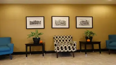 a waiting room with a chair and three pictures on the wall at Holiday Inn Express and Suites Montgomery by IHG in Montgomery