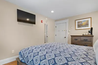 a bedroom with a bed and a tv on the wall at Brook Bound Inn in Wilmington
